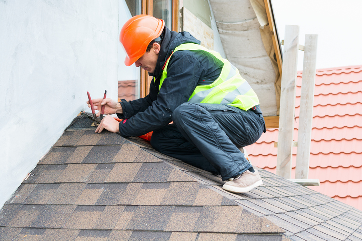 Roofer builder worker dismantling roof shingles Detroit