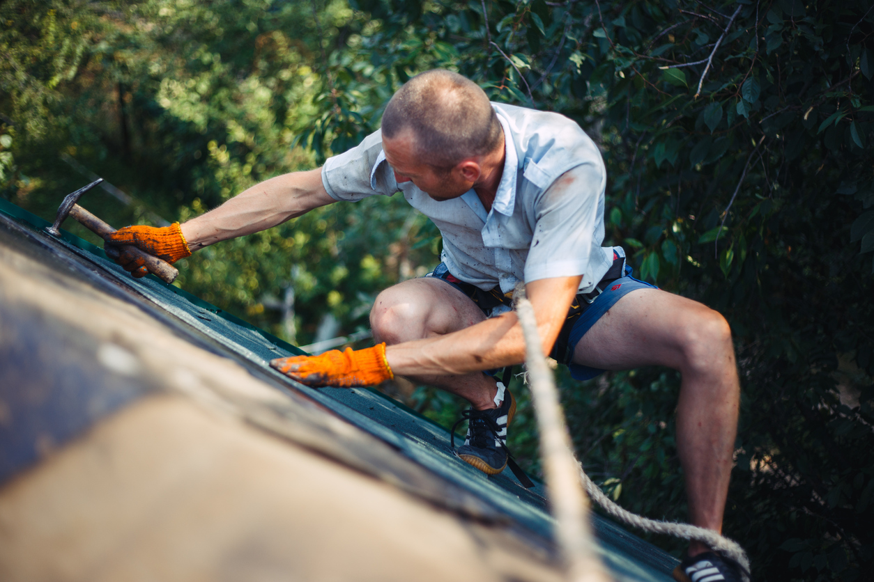 Roofer installs bitumen roof shingles.