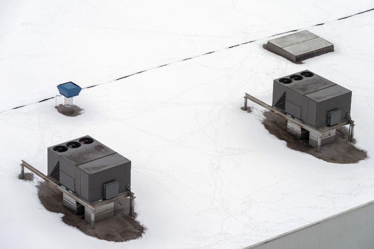 Rooftop HVAC units on the commercial roof with snow on it