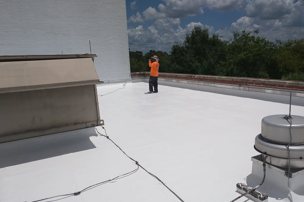 Roofer inspecting a commercial flat roof, EPDM Roofing. Roofer inspecting a commercial flat roof, white EPDM, construction crew